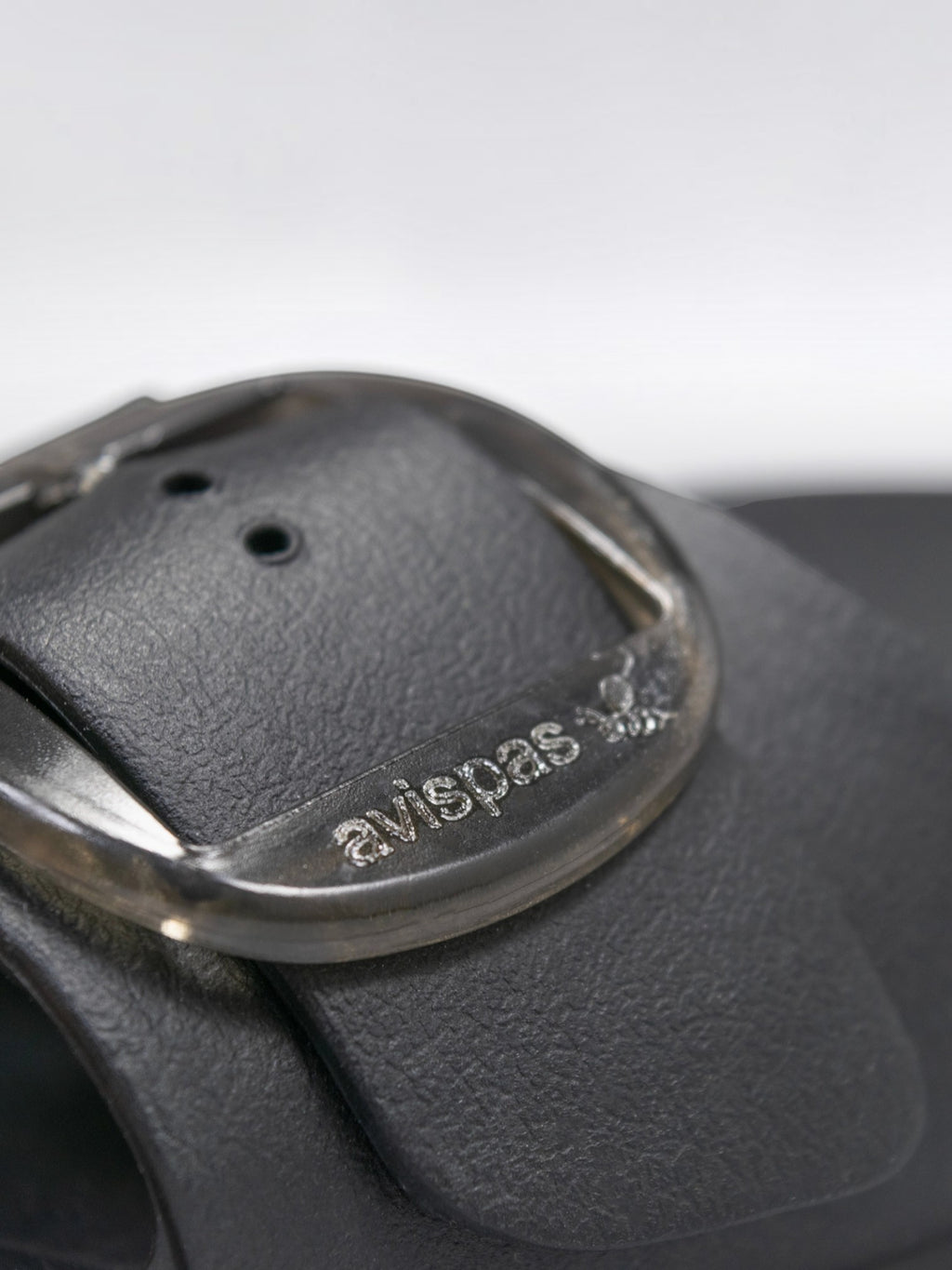 Close-up of a black BROCK AVISPAS Milano EVA sandal featuring a translucent adjustable oval buckle