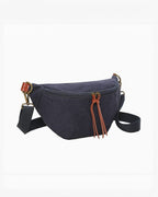 Banane INES DELAURE en toile bleu marine et PU marron, avec deux poches zippées et détails en cuir.