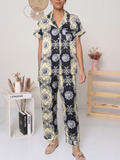Model wearing a BROCK BELLE COM'ELLE satin pajama set with a black and yellow baroque print and short sleeves.
