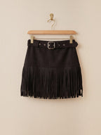 BROCK black faux suede mini skirt with fringe hem and matching belt featuring a silver buckle hanging on a hanger