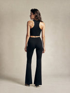 Model wearing BROCK black high-waisted flared leggings and a matching racerback crop top, back view.