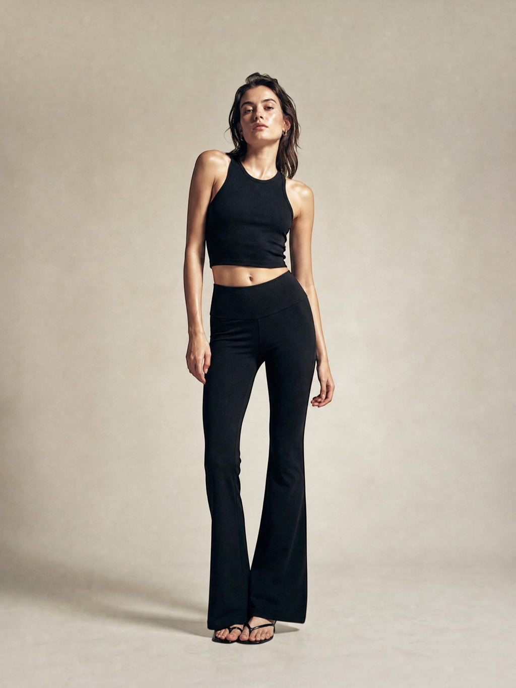 Model wearing BROCK black high-waisted flared leggings and a matching ribbed crop top against a neutral background.