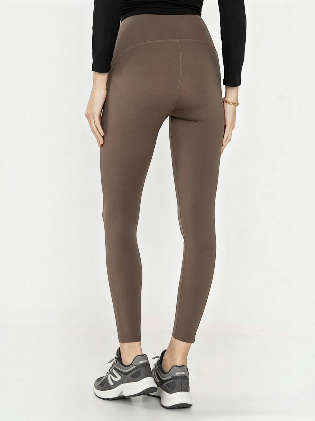 Back view of BROCK high-waisted brown polyamide yoga leggings worn with sneakers for sports and pilates.