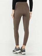 Back view of BROCK high-waisted brown polyamide yoga leggings worn with sneakers for sports and pilates.