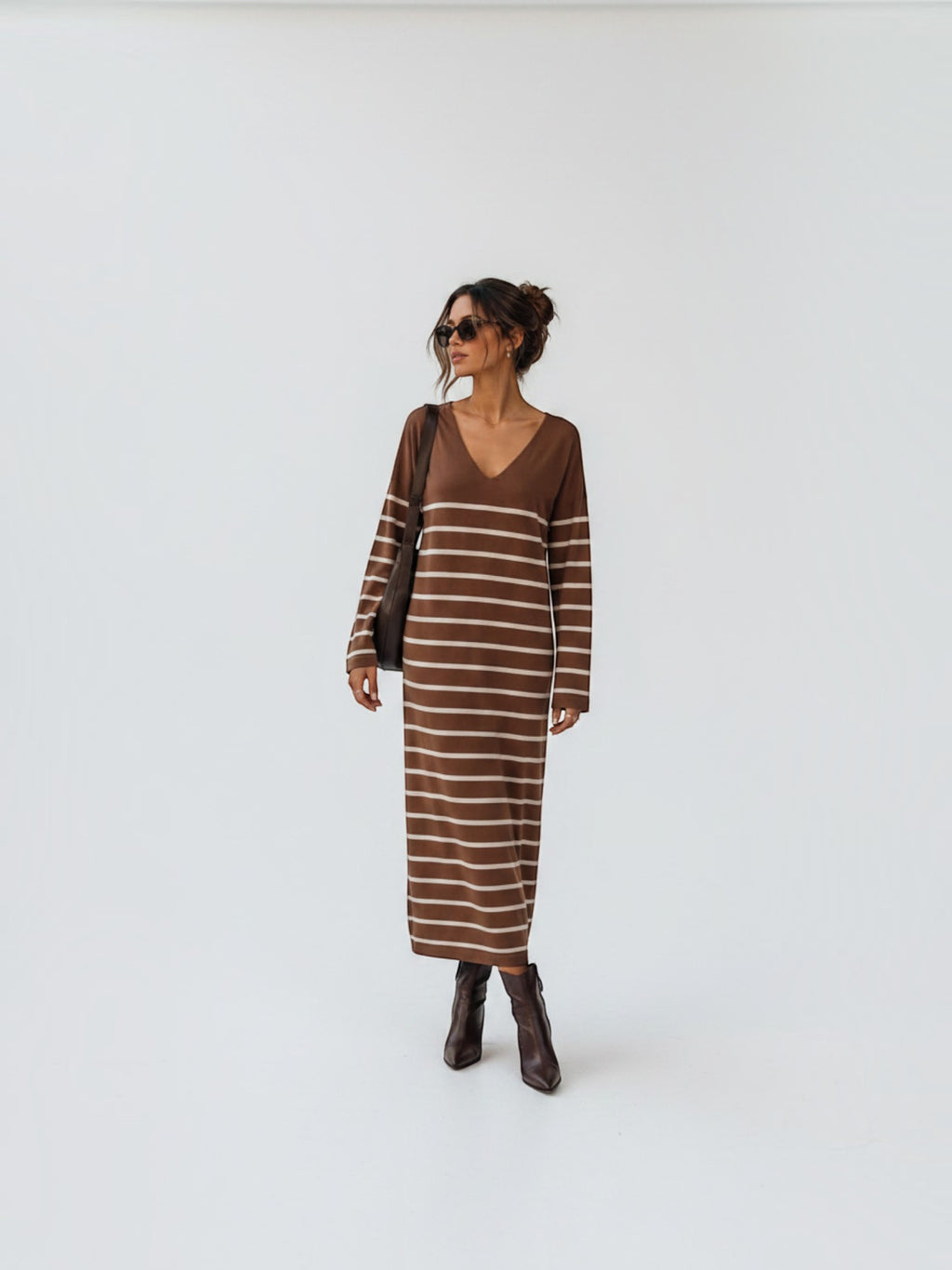 BROCK long brown striped maxi dress with V-neck and long sleeves worn by a woman with brown boots and sunglasses