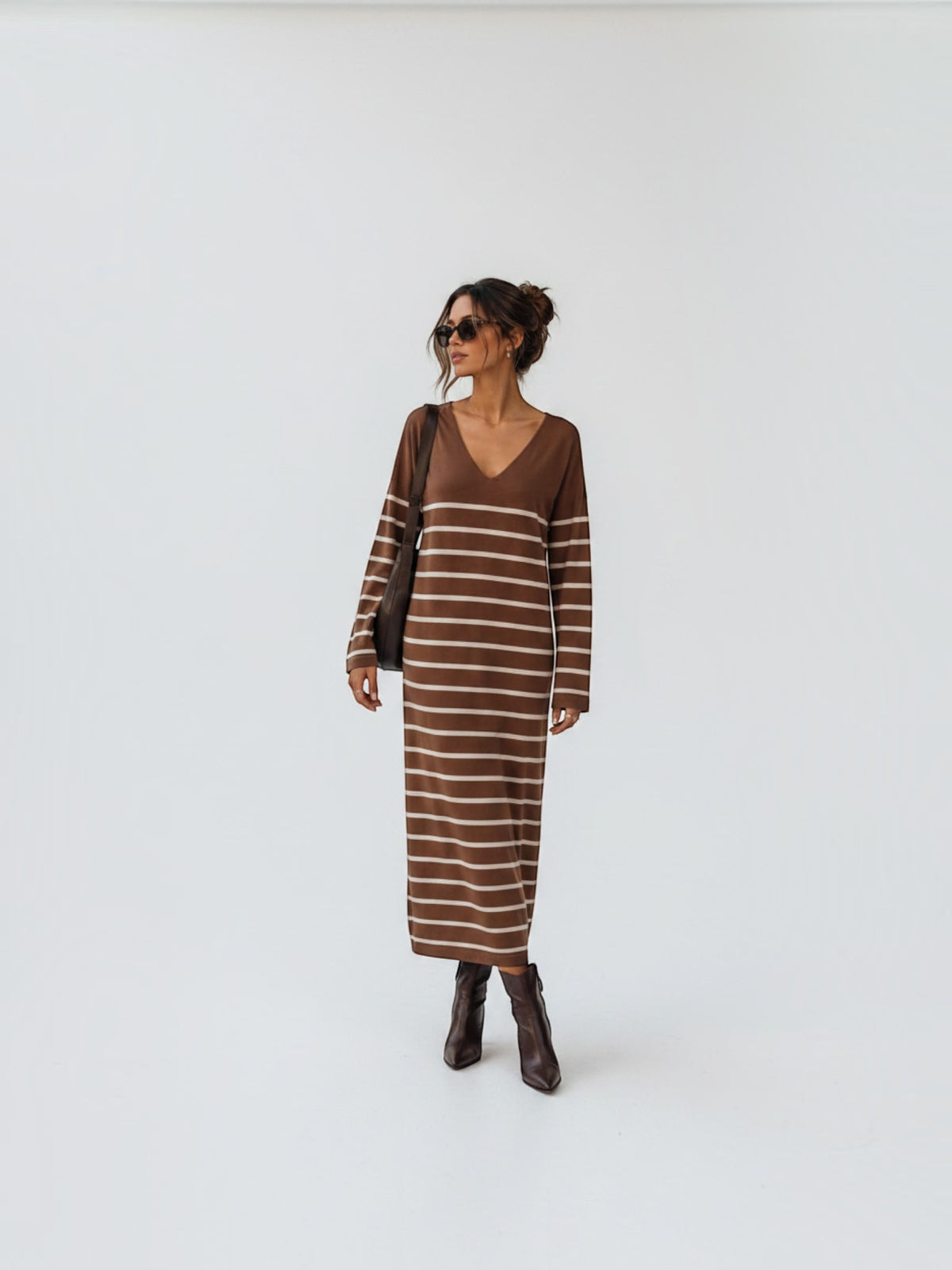 BROCK long brown striped maxi dress with V-neck and long sleeves worn by a woman with brown boots and sunglasses