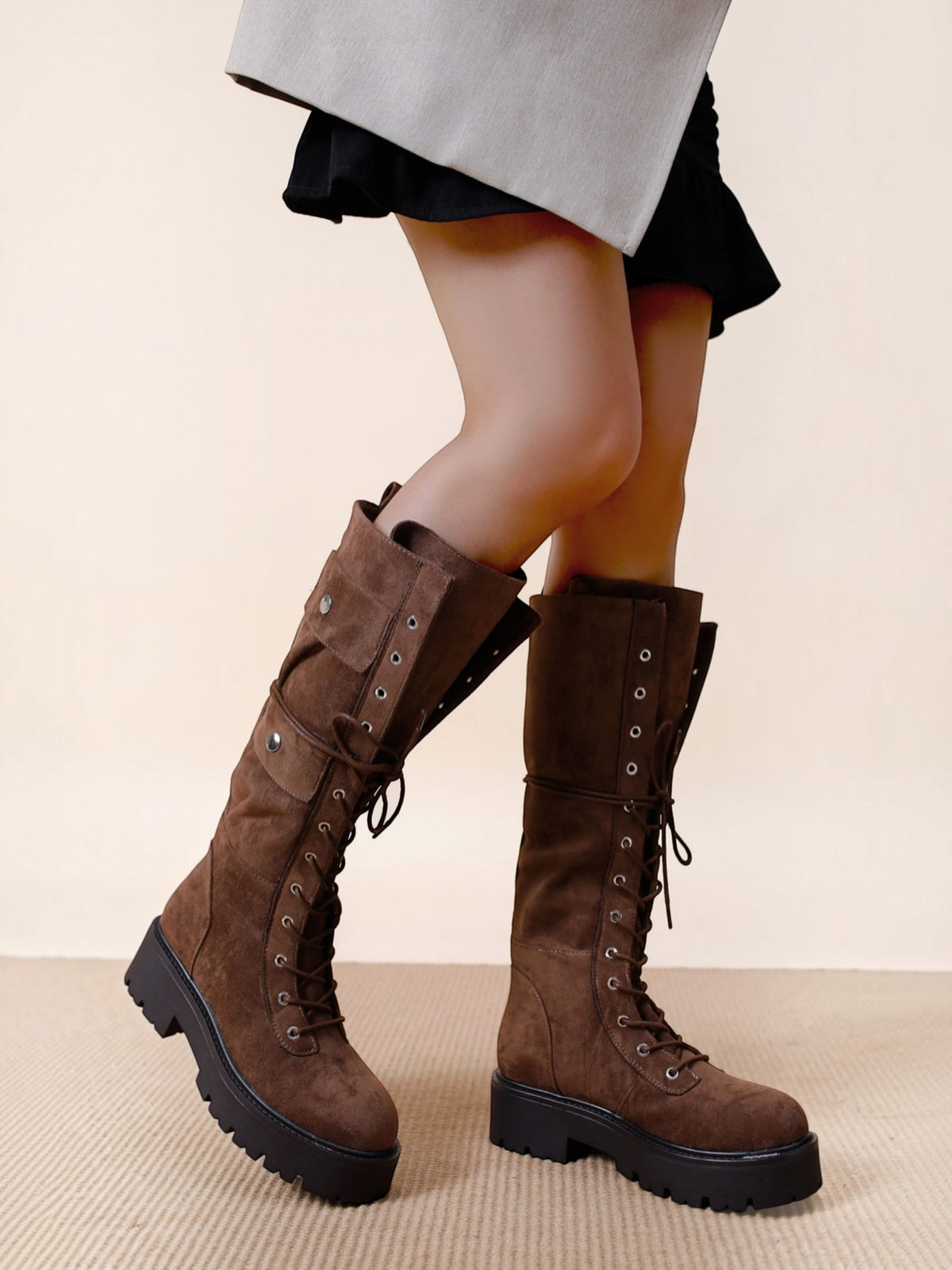 BROCK brown suede lace-up biker boots with decorative pockets, gold hardware, and thick lug soles on a model
