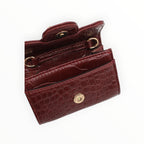 BROCK mini crossbody bag in burgundy faux crocodile leather with gold hardware and snap closure