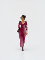 BROCK long striped V-neck maxi dress in burgundy worn by a woman with brown boots and a shoulder bag