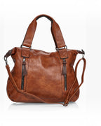 BROCK COLMA large cognac faux leather tote bag with decorative zipper tassels, sturdy handles, and shoulder strap.