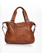 BROCK COLMA large cognac faux leather tote bag with sturdy handles and a back zipper pocket.