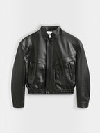 BROCK Copperose black faux leather cropped jacket with structured shoulders, mandarin collar, and flap pockets.