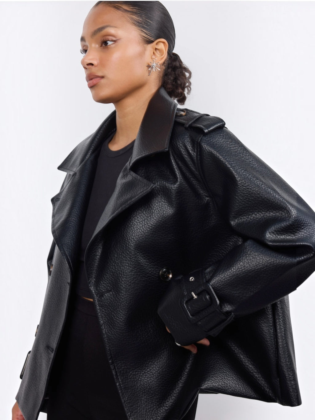 Model wearing a black BROCK Copperose double-breasted faux leather jacket with notched lapels and buttoned shoulders.