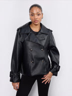 Model wearing a black BROCK Copperose double-breasted faux leather jacket with notched lapels and buckled cuffs.