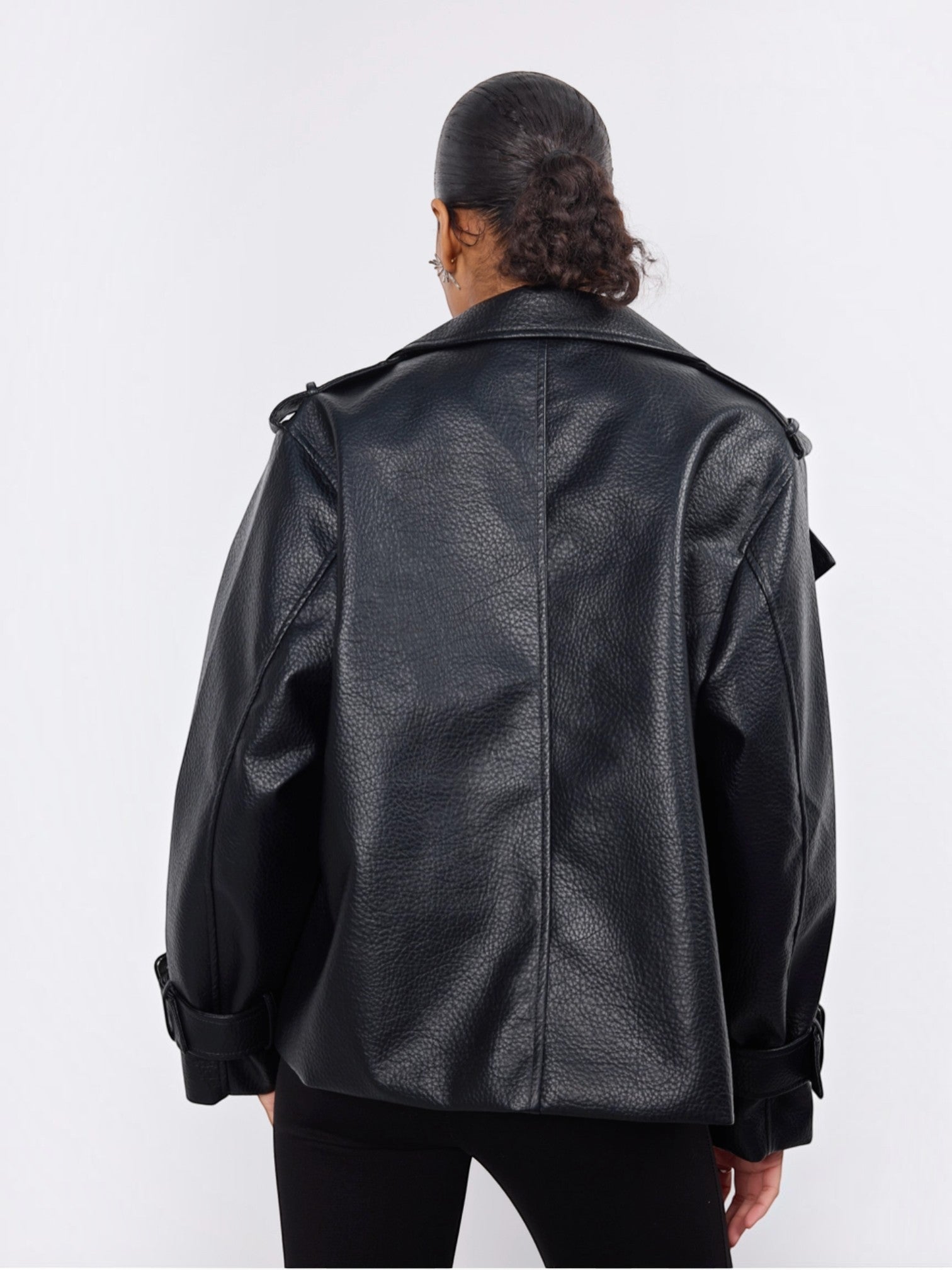 Back view of a BROCK Copperose black faux leather double-breasted jacket with shoulder epaulettes on a model.