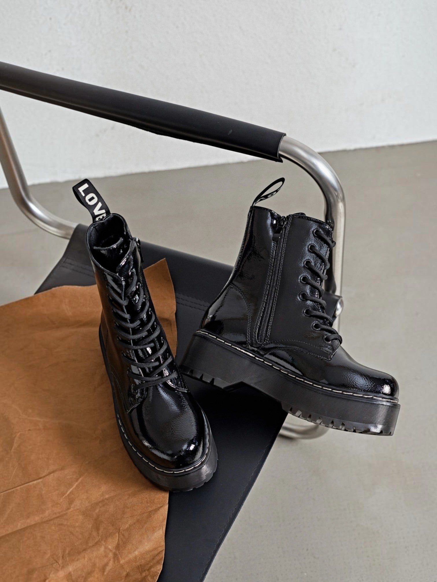 BROCK ERYNN black patent combat boots with platform lug soles, lace-up front, side zip, and LOVE heel pull tabs.