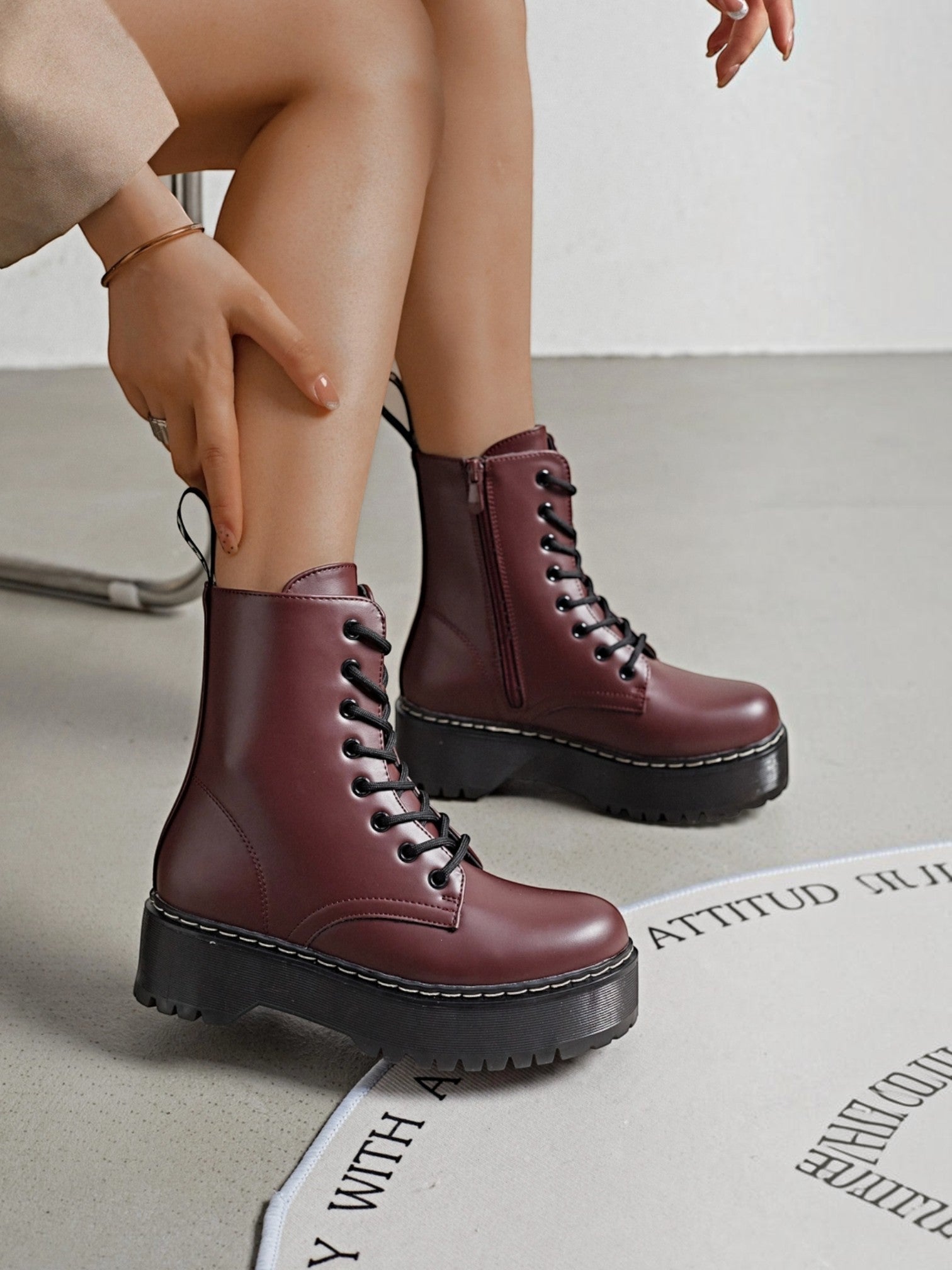 BROCK ERYNN burgundy combat boots with platform lug soles, black laces, and white contrast stitching on a model