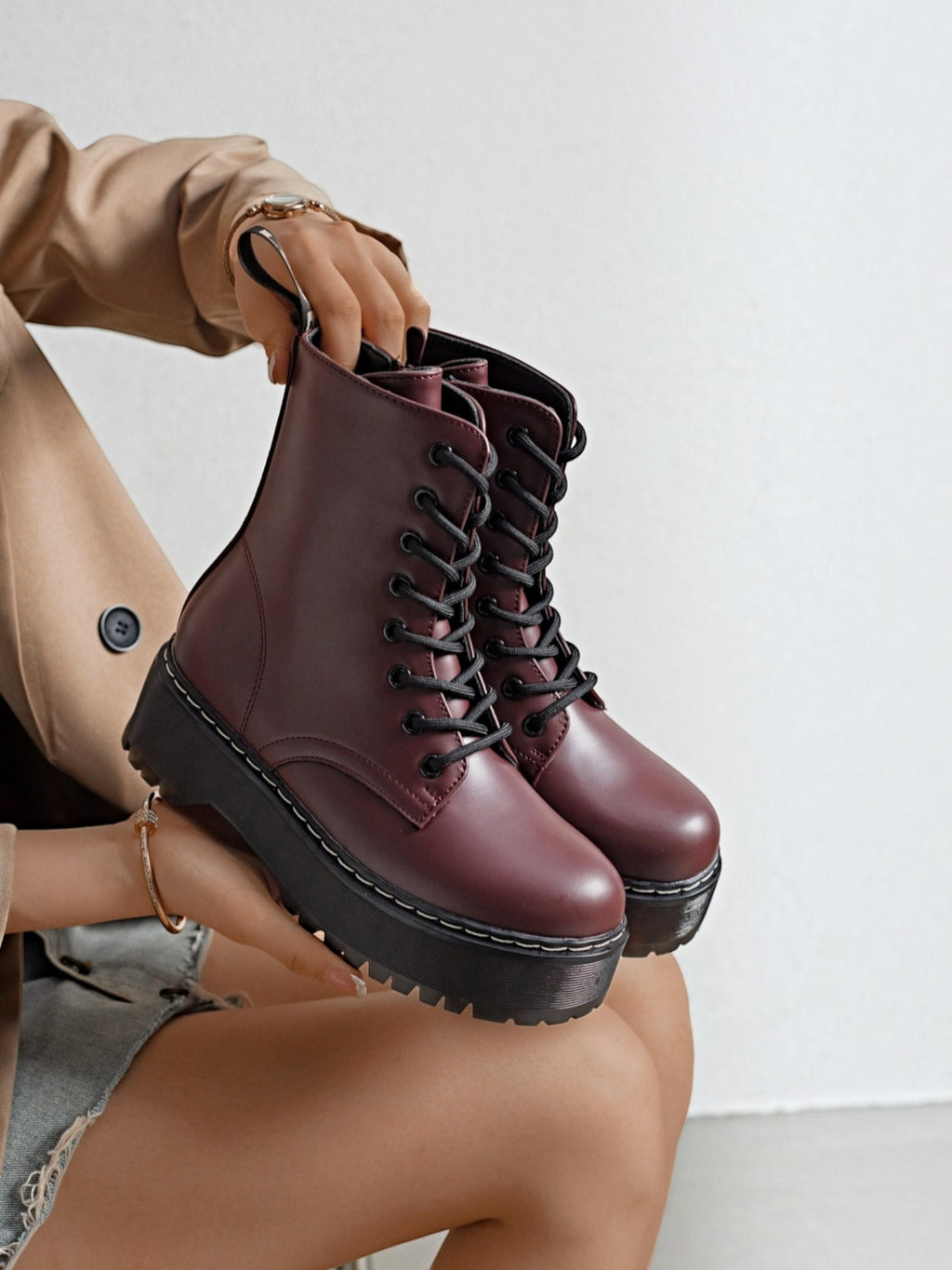 BROCK ERYNN burgundy combat boots with platform lug soles, black laces, and white contrast stitching