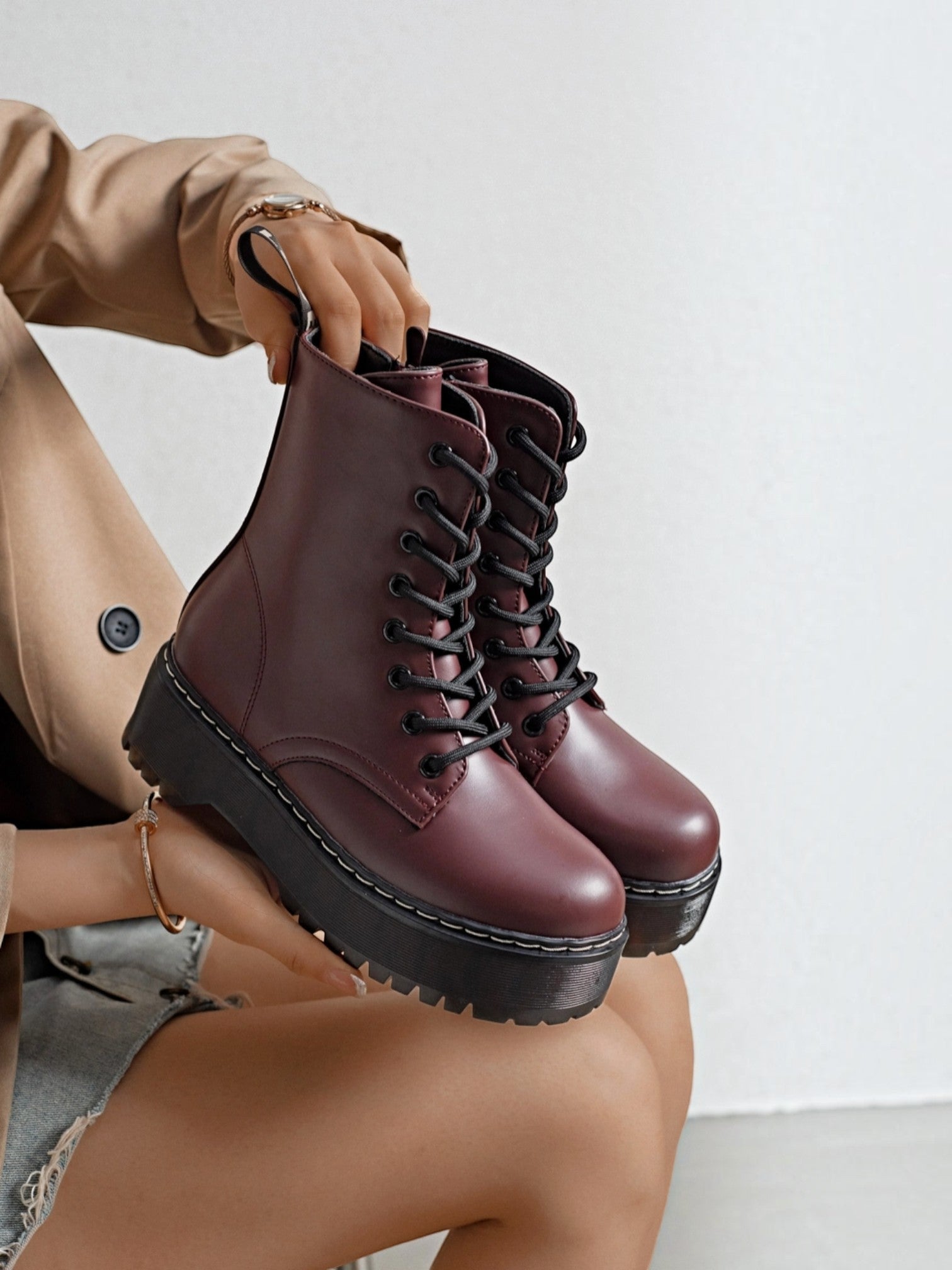 BROCK ERYNN burgundy combat boots with platform lug soles, black laces, and white contrast stitching
