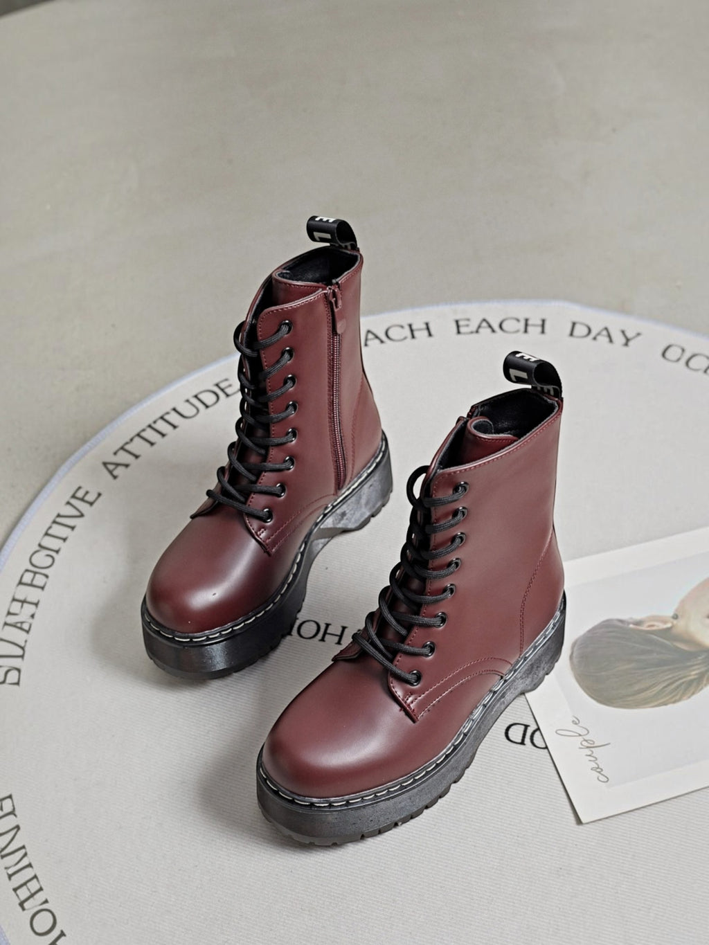 BROCK ERYNN burgundy combat boots with platform lug soles, black laces, side zippers, and white contrast stitching.