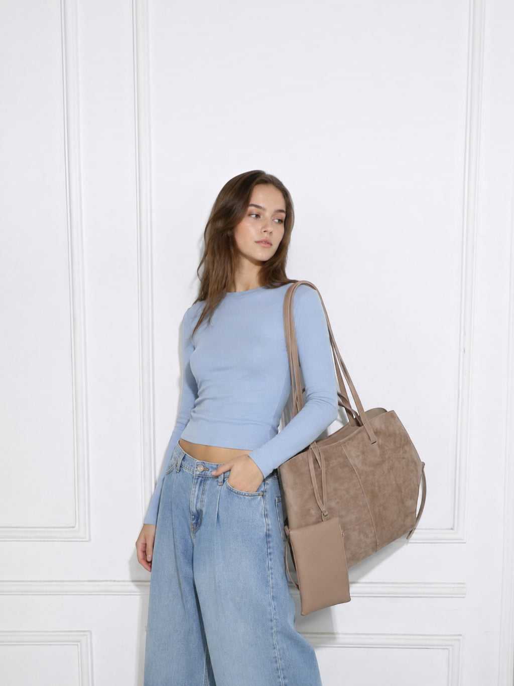 Model carrying a BROCK GALLANTRY Elyssa beige synthetic tote bag with a detachable pouch and gold hardware.