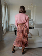 BROCK long pleated skirt with geometric print and satin finish worn with a pink sweater and brown boots