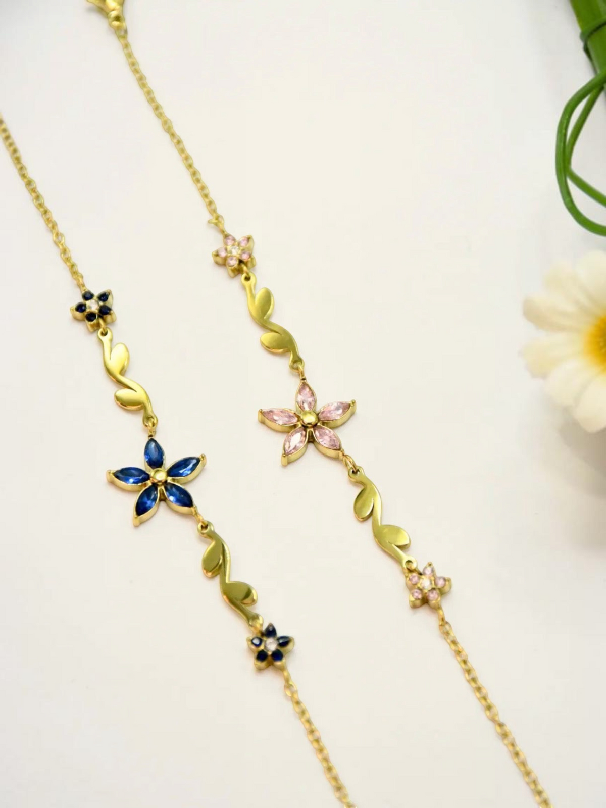 BROCK gold stainless steel chain bracelet featuring blue and pink rhinestone flower and leaf motifs
