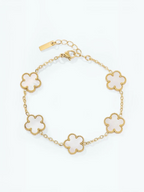 BROCK gold-tone stainless steel bracelet featuring five white flower-shaped charms with beaded edges