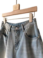 BROCK Golden Days high-waisted denim skort in light blue cotton with belt loops and stitched details on a hanger