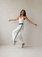 Woman wearing BROCK Golden days white wide-leg viscose pants with black side stripes and adjustable leg cuffs