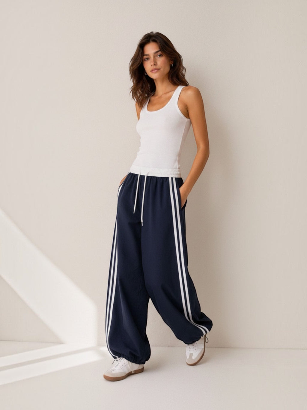 Model wearing BROCK Golden days wide-leg navy trousers with white side stripes, elastic waist, and drawstring cuffs.