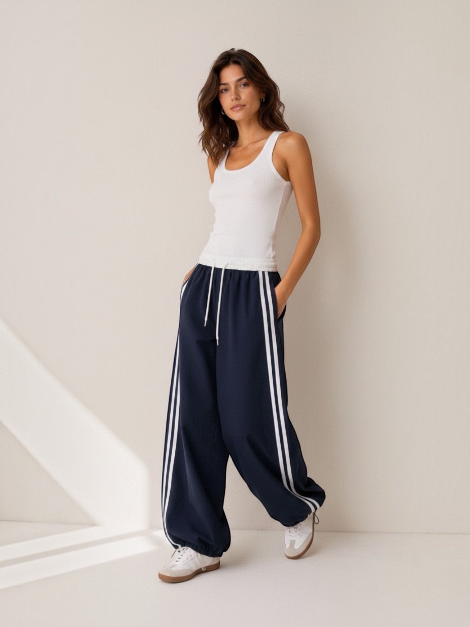 Model wearing BROCK Golden days wide-leg navy trousers with white side stripes, elastic waist, and drawstring cuffs.