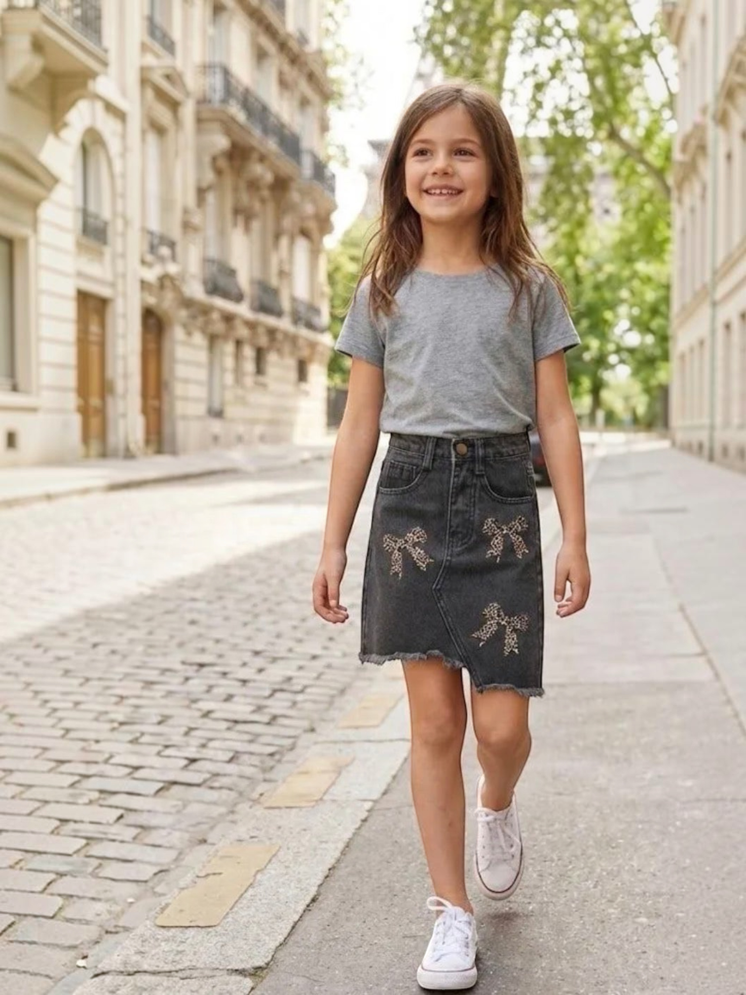 BROCK GRASSTAR girl's black denim skirt with leopard print bow details and frayed hem worn by a smiling child