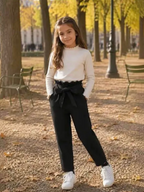 Young girl wearing BROCK GRASSTAR black high-waisted trousers with a tie belt in a park during autumn