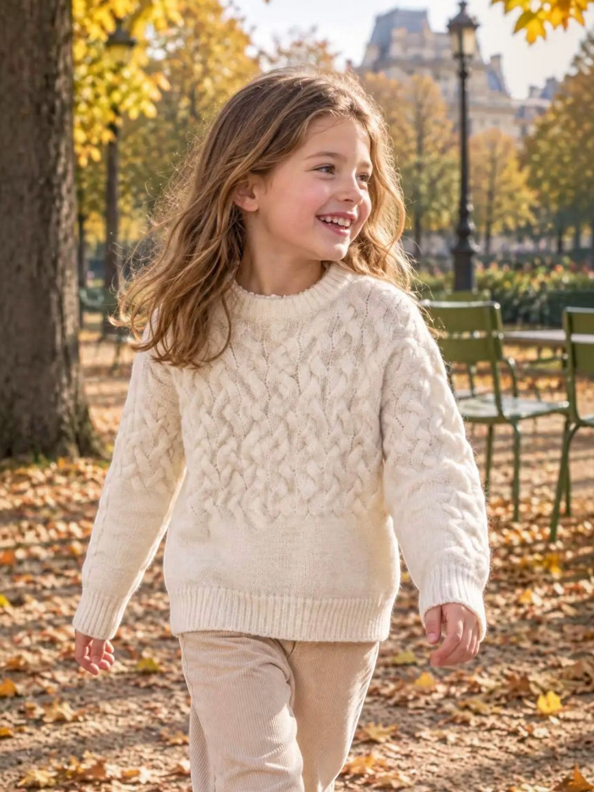 A young girl wearing a cream-colored BROCK GRASSTAR cable-knit sweater with a round neck in an autumn park.