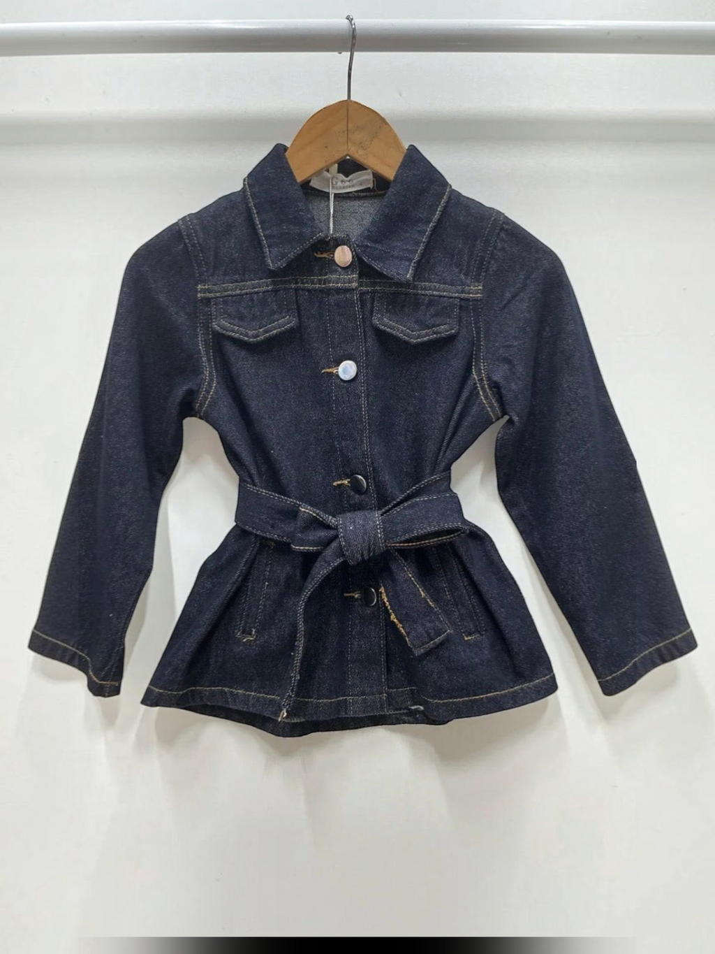 BROCK Grasstar dark blue denim jacket with a belted waist, collar, and button-up front on a wooden hanger.