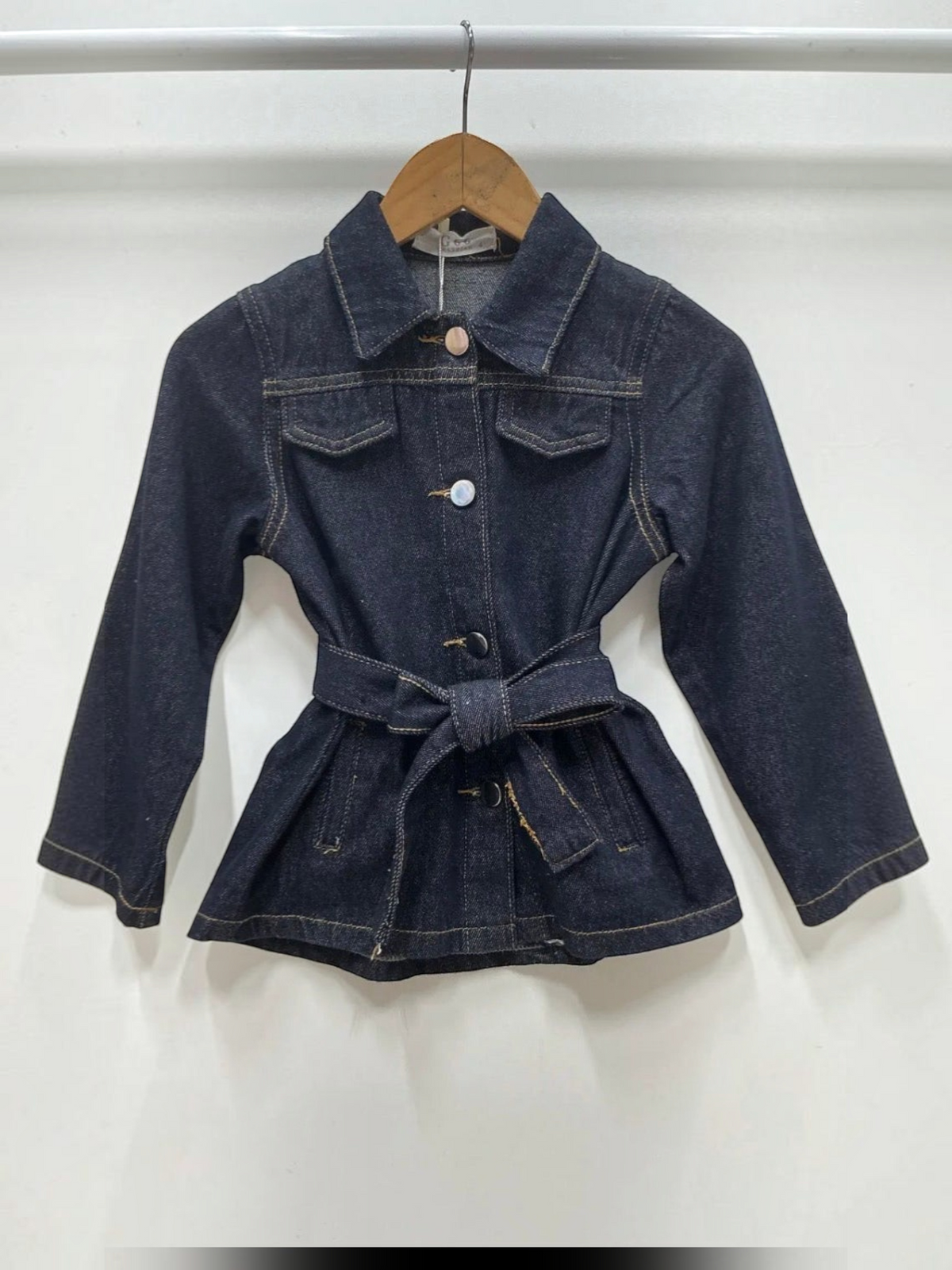 BROCK Grasstar dark blue denim jacket with a belted waist, collar, and button-up front on a wooden hanger.
