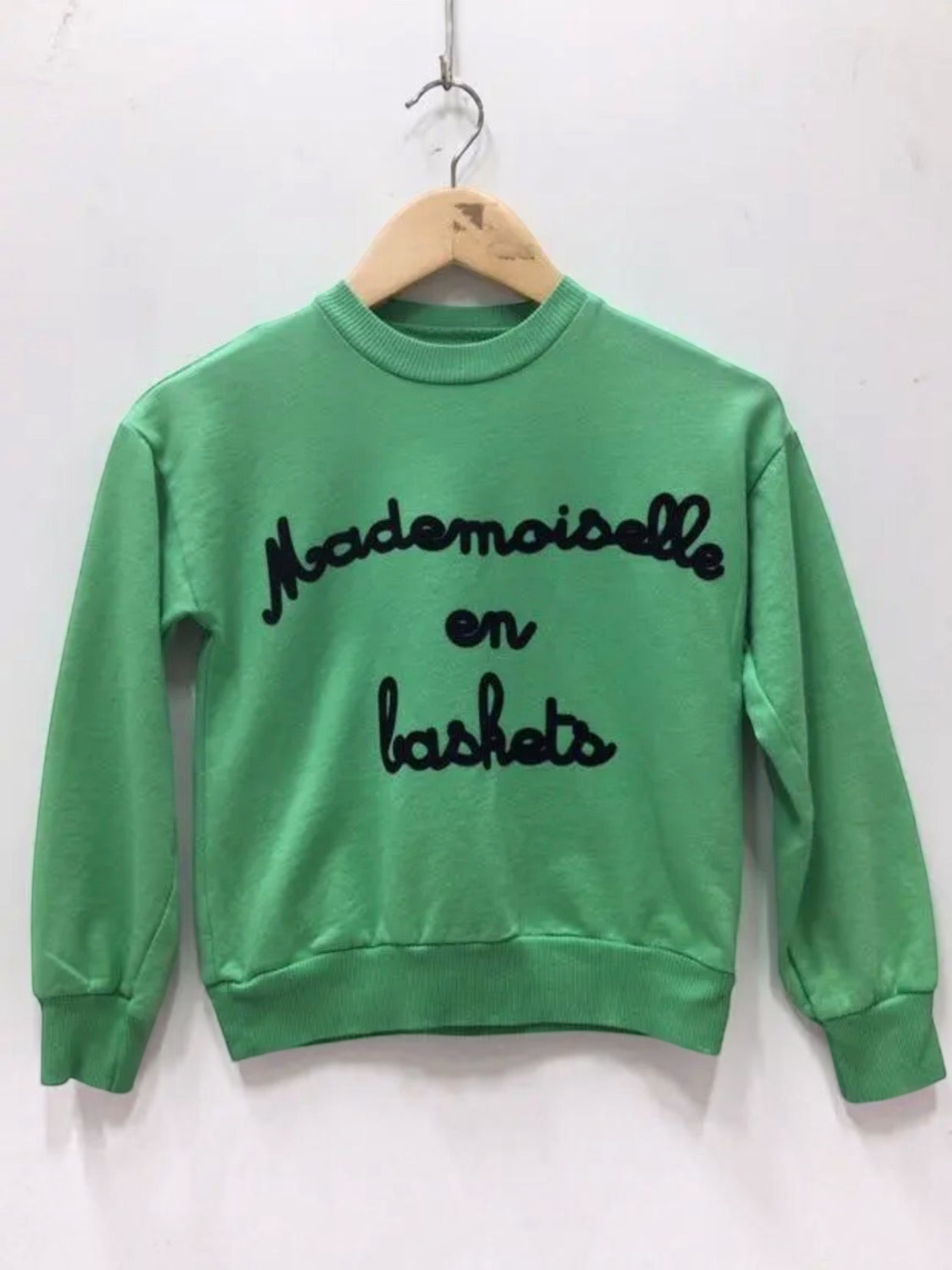 BROCK green cotton children's sweatshirt with Mademoiselle en baskets text embroidery on a wooden hanger