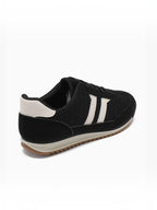 BROCK JOIA black low-top sneakers with white side stripes, rounded toe, and a thick, textured gum-colored sole.