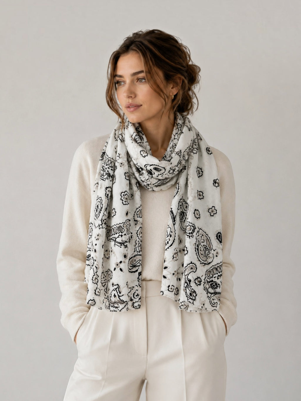 BROCK LINETA white and black bandana print scarf with fringed edges worn by a woman in a cream sweater