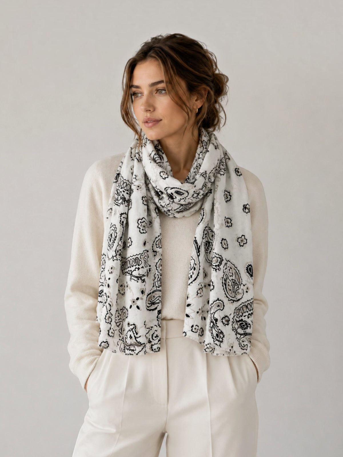 BROCK LINETA white and black bandana print scarf with fringed edges worn by a woman in a cream sweater