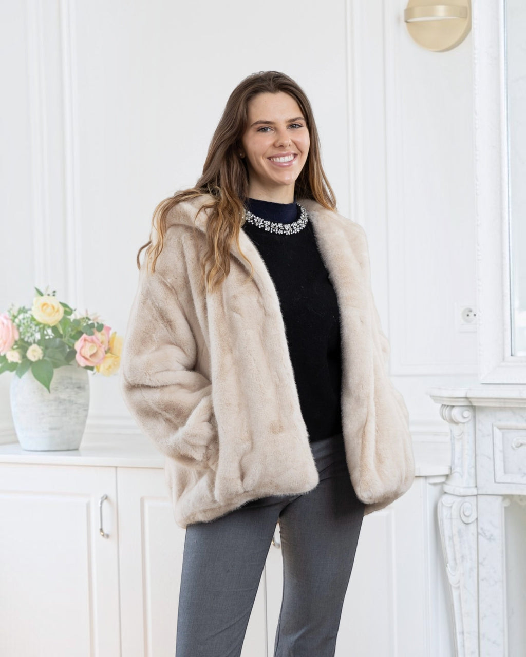 BROCK LINETA beige faux fur hooded coat with a velvet-touch finish worn by a smiling woman in a bright room.