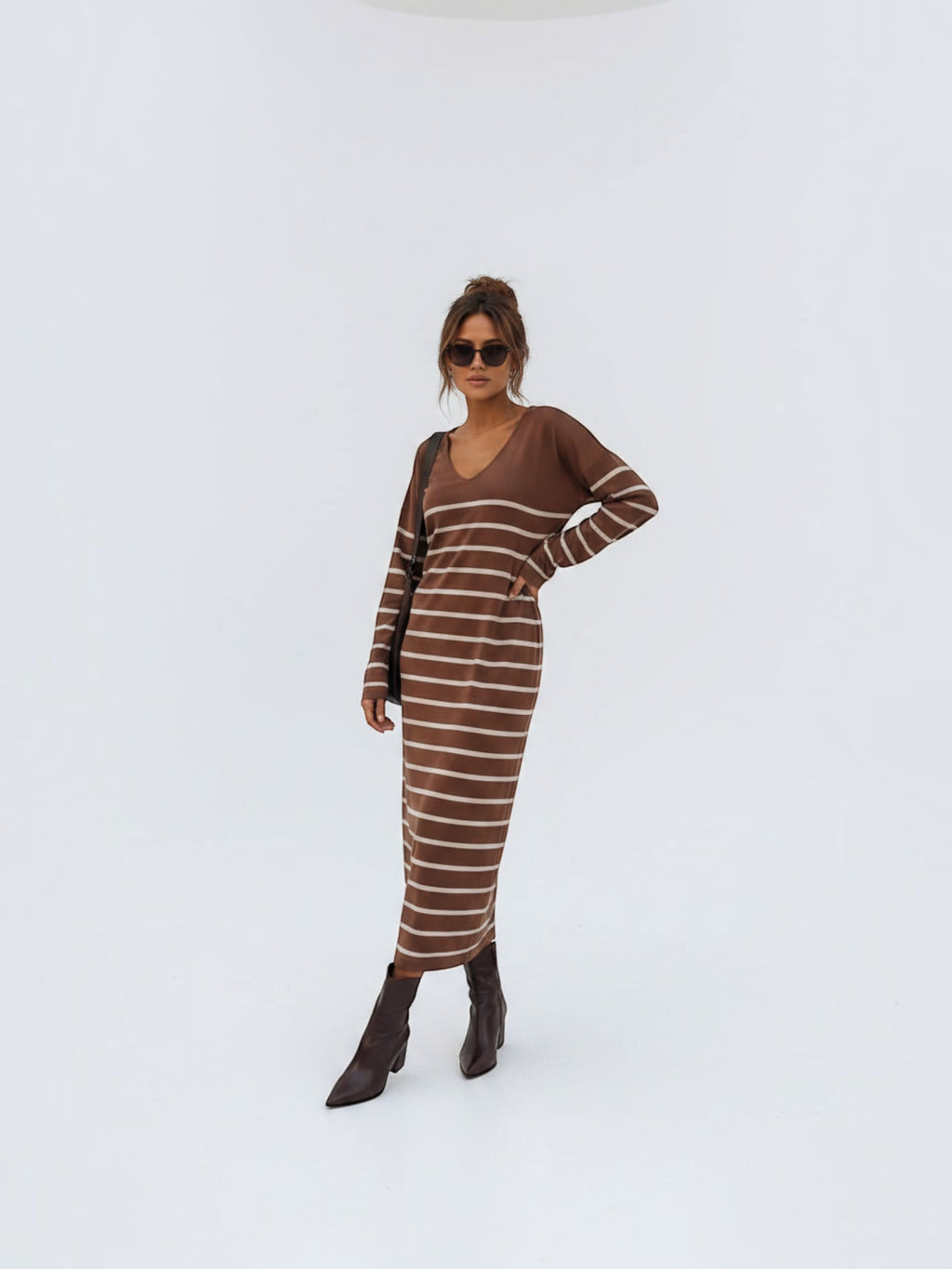 BROCK long brown striped maxi dress with V-neck and long sleeves worn by a model with brown boots and sunglasses