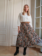 BROCK LOVIE & CO long pleated skirt with geometric print, satin finish, and elastic waist worn by a blonde model.