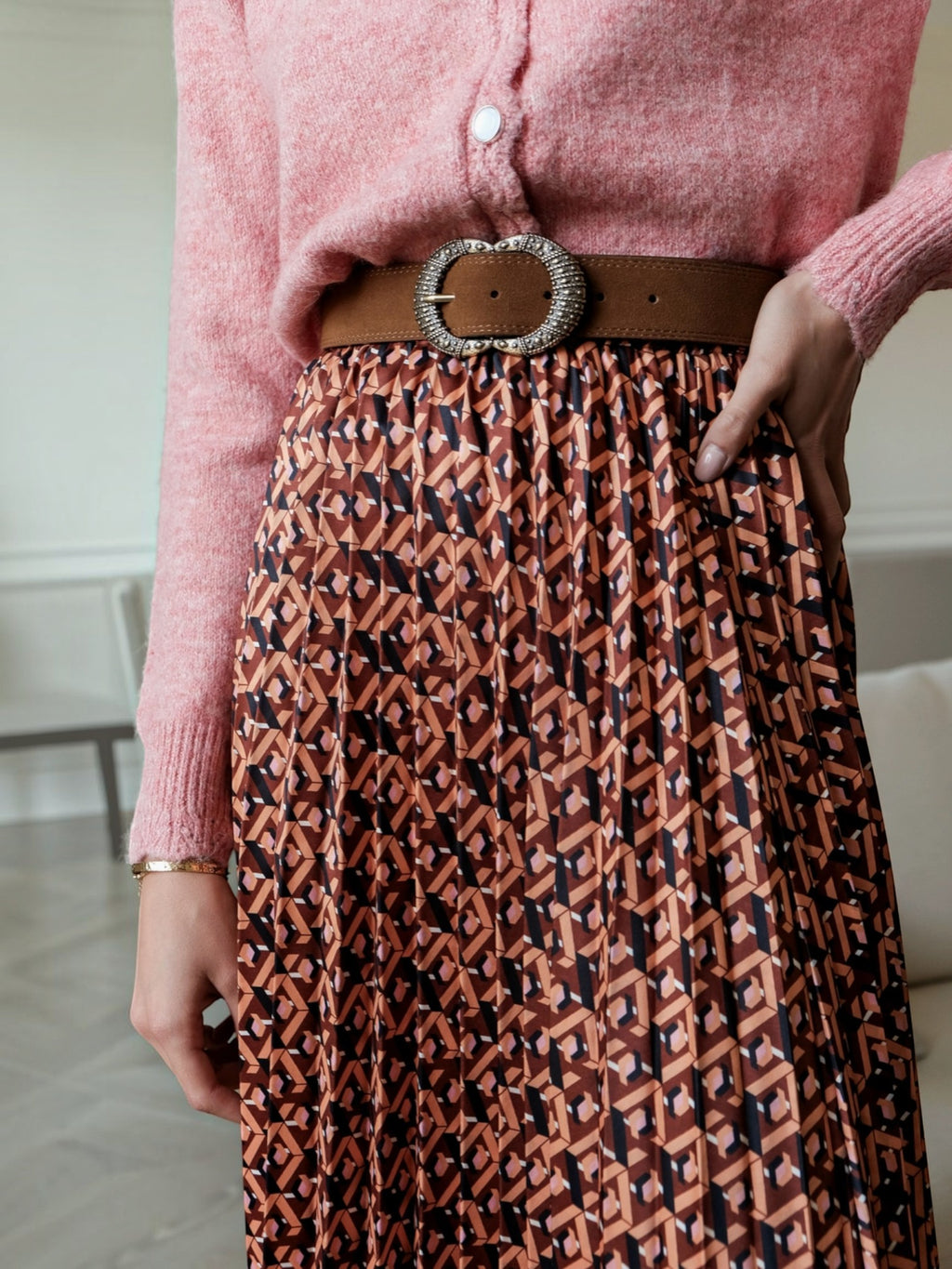 BROCK LOVIE & CO long pleated skirt with geometric print, satin finish, and elastic waist worn with a brown belt