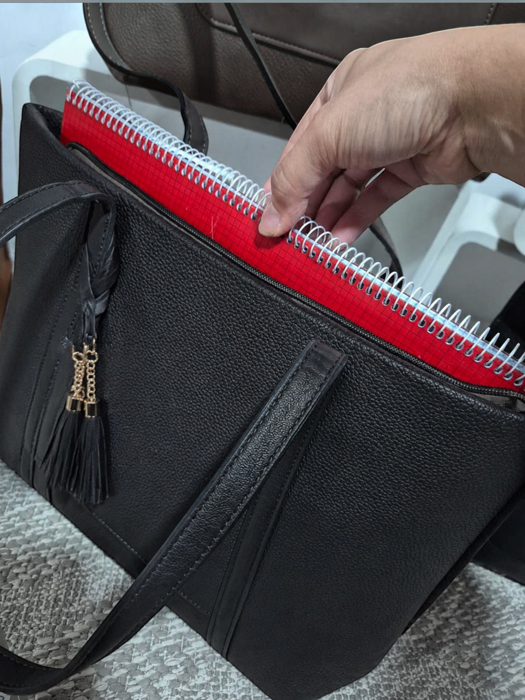 BROCK MIA LAROUGE black leather university shoulder bag with a red notebook inside and a decorative tassel.