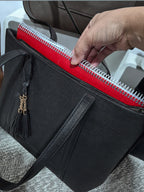 BROCK MIA LAROUGE black leather university shoulder bag with a red notebook inside and a decorative tassel.