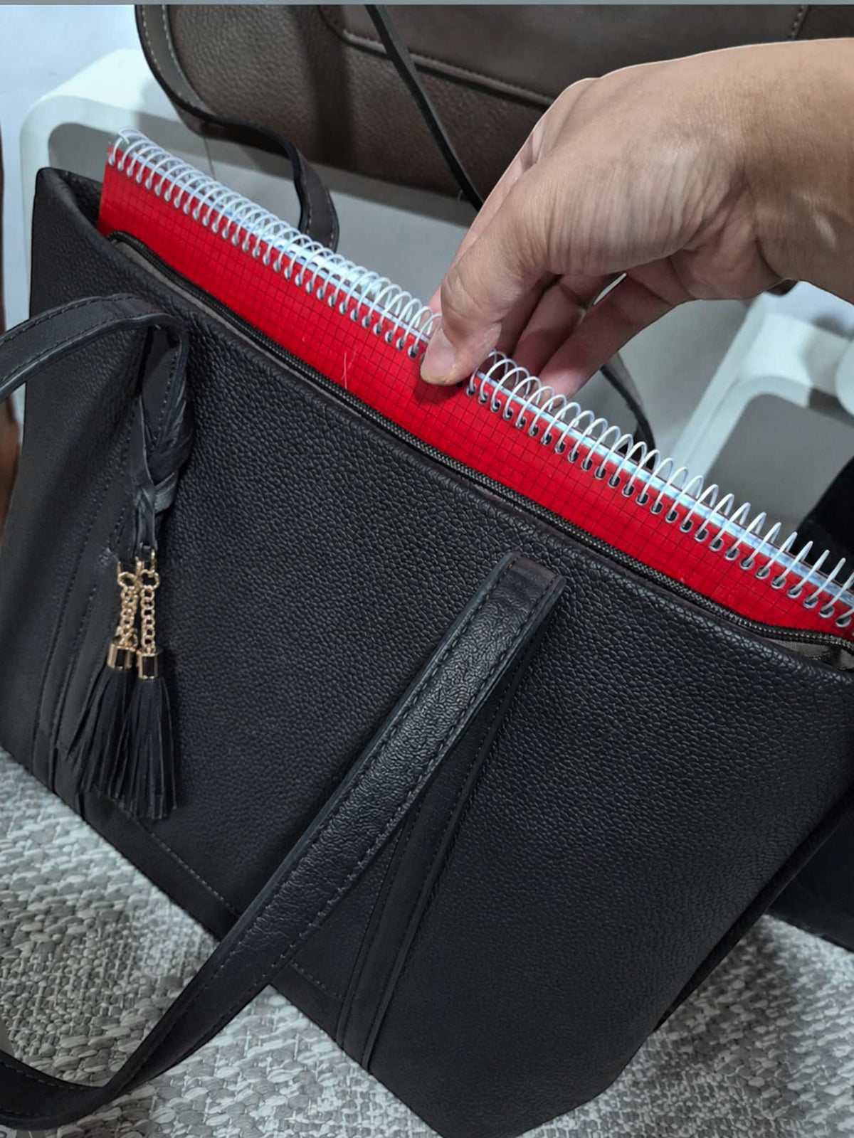 BROCK MIA LAROUGE black leather university shoulder bag with a red notebook inside and a decorative tassel.