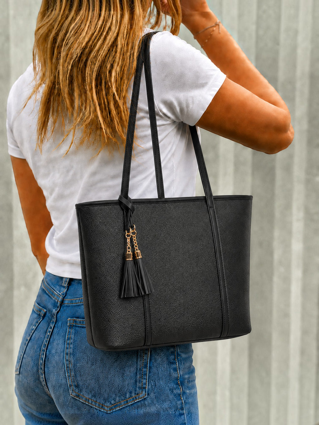 BROCK MIA LAROUGE black structured shoulder bag with tassel detail worn by a woman in a white t-shirt and jeans