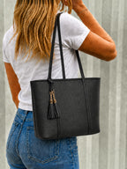 BROCK MIA LAROUGE black structured shoulder bag with tassel detail worn by a woman in a white t-shirt and jeans